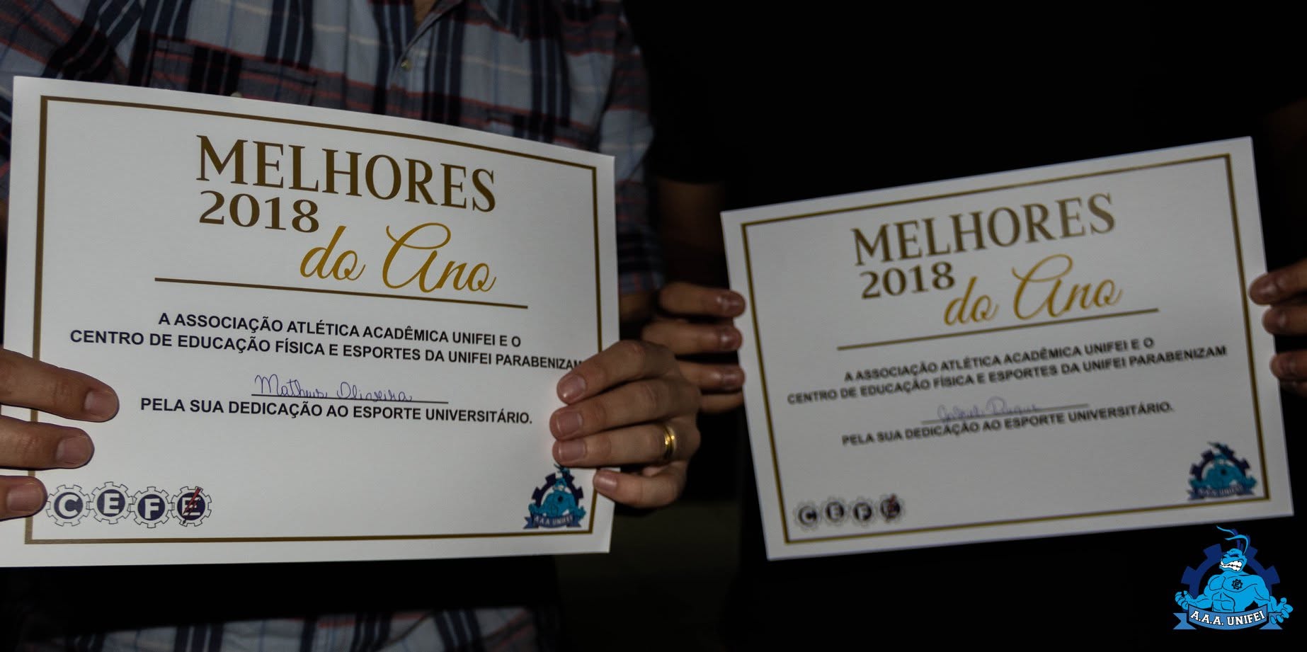 Detalhe de dois certificados Melhores 2018 do Ano segurados para a câmera.